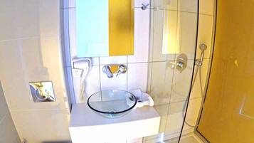 A bathroom with a glass shower enclosure, a white sink with a glass bowl, and a toilet.