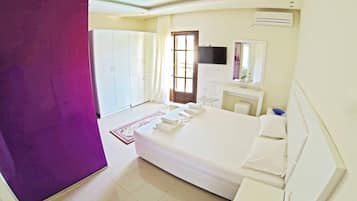 Habitación de hotel con cama, escritorio, silla, armario y unidad de aire acondicionado.