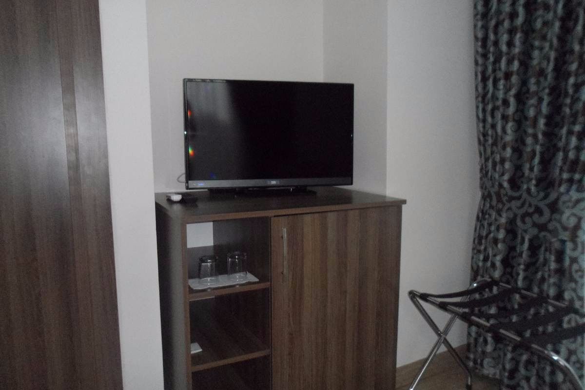 Una habitación pequeña con una televisión sobre un mueble de madera, una silla y una cortina estampada.