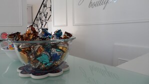 A glass bowl filled with assorted candies on a table in a room with white walls and a staircase. - Zen Inn Boutique (Sarkoy)