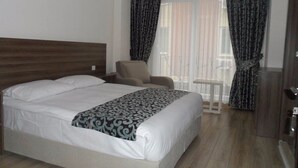 A hotel room with a large bed, a chair, a small table, and a wardrobe. - Zen Inn Boutique (Sarkoy)