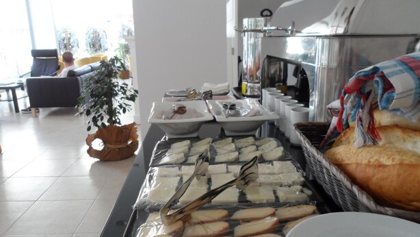 A buffet with various cheeses and breads, a coffee machine, and a seating area with a couch and a plant. - Zen Inn Boutique (Sarkoy)