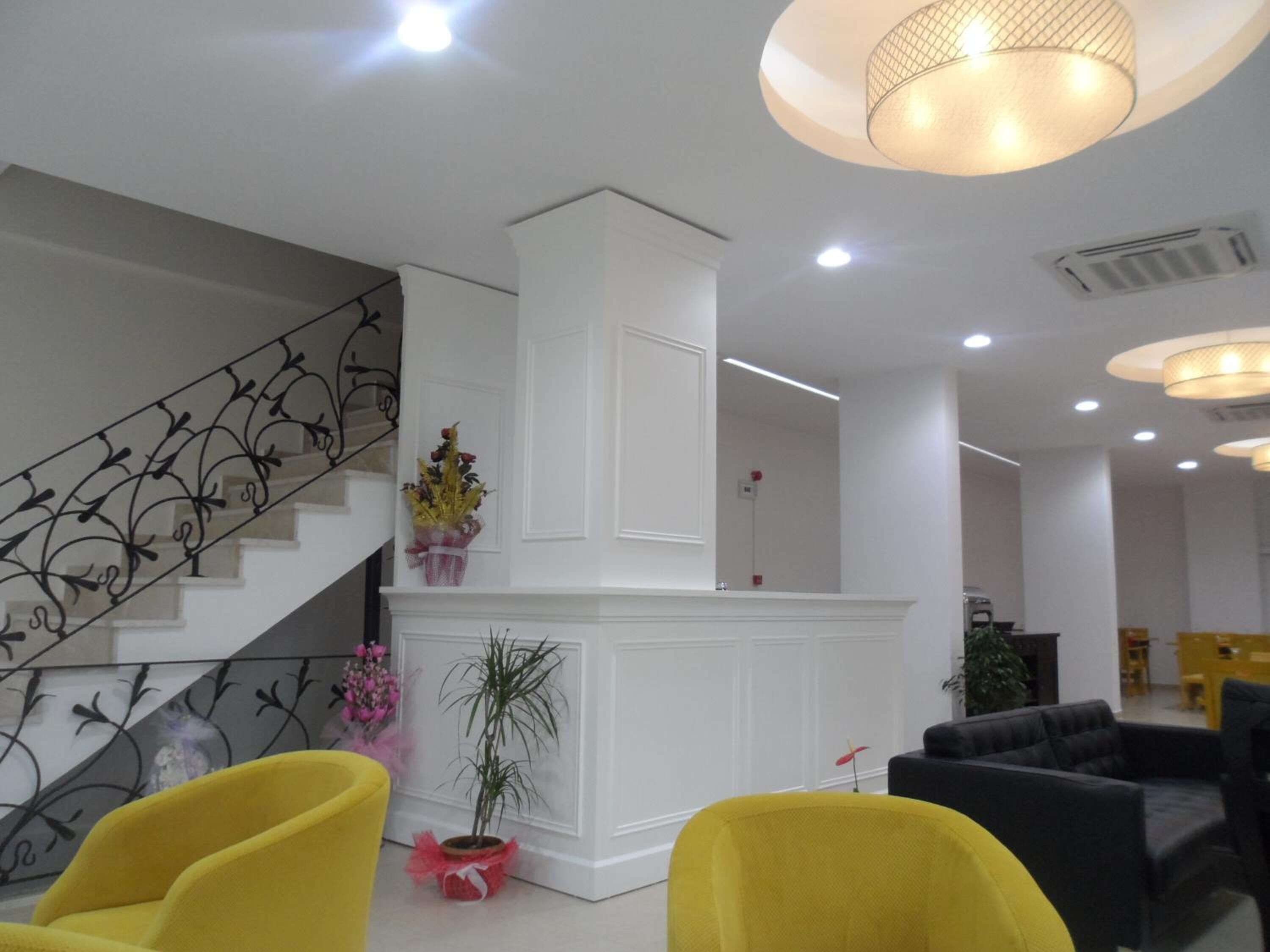 A modern interior with a staircase, a reception desk, and seating areas.