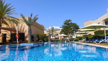 Una piscina al aire libre, camas de piscina gratis, sombrillas
