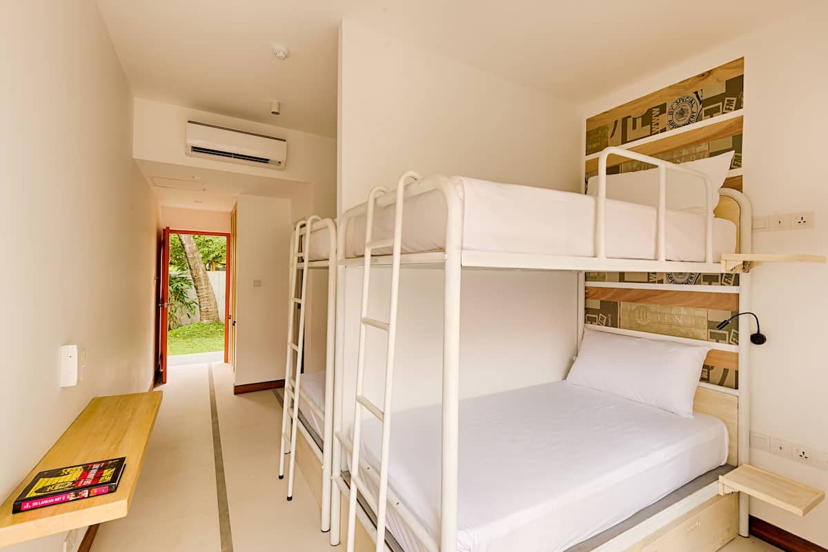 Habitación con literas, un escritorio de madera y una estantería.