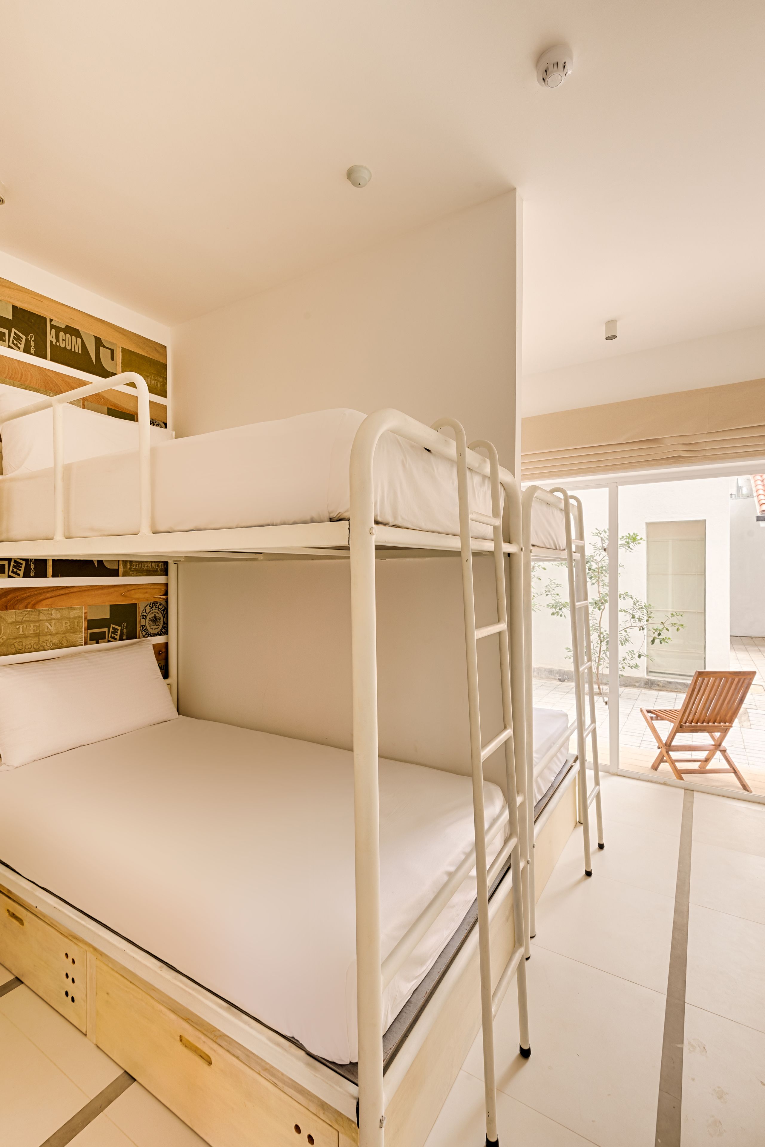 Une chambre avec un lit superposé, une échelle en bois, une chaise et un mur orné d’une affiche.
