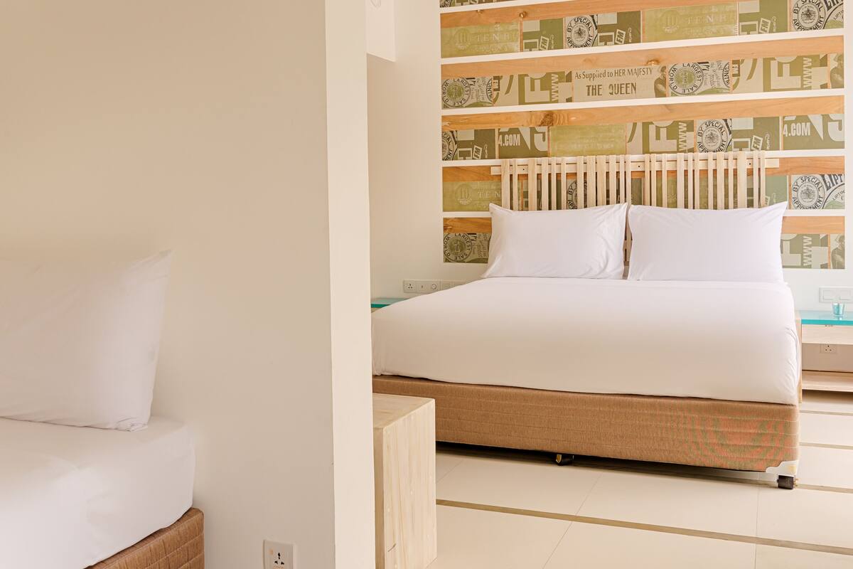 Una habitación de hotel con una cama, una mesita de noche y una pared decorada con papel tapiz estampado.