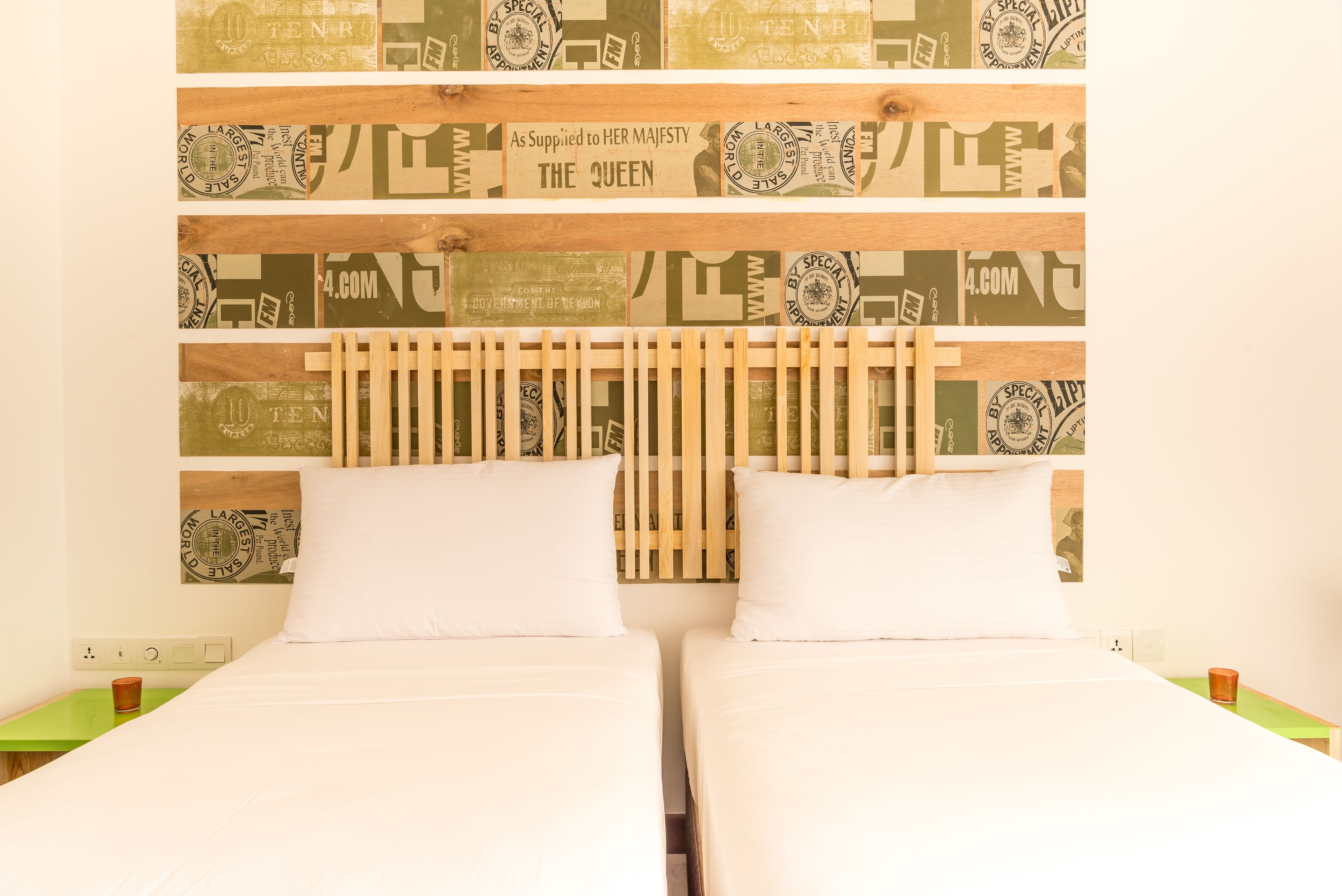 A double bed with white linens, a wooden headboard, and a wall with vintage-style wallpaper.
