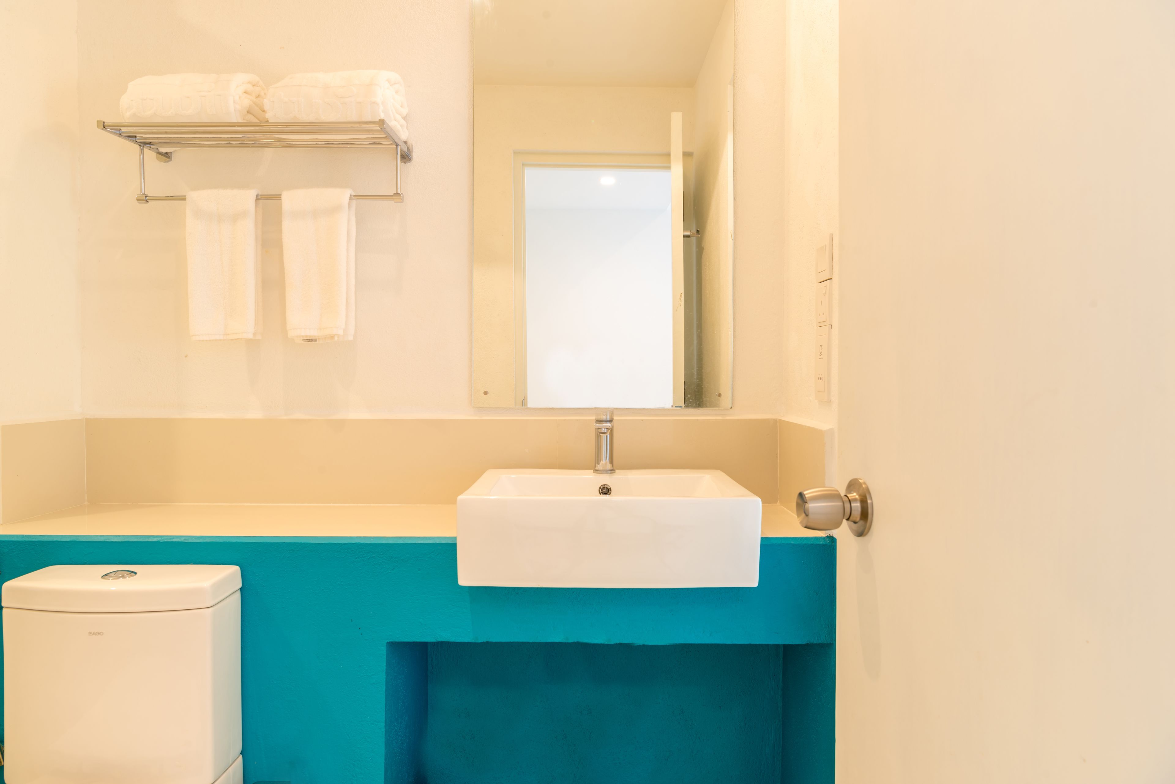 Une salle de bain avec un lavabo blanc, un miroir et un porte-serviettes avec deux serviettes.