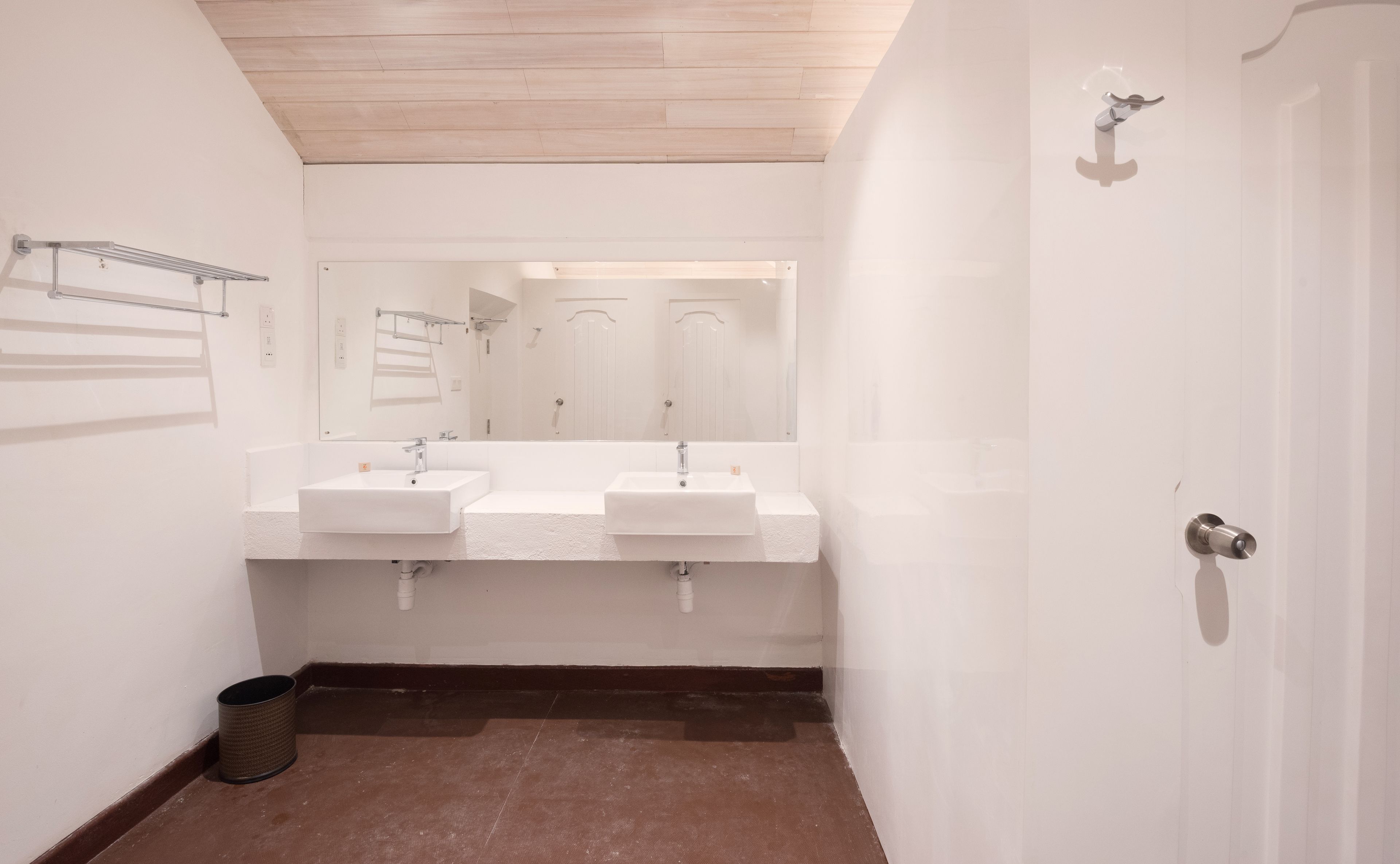 A bathroom with two sinks, a mirror, and a door.