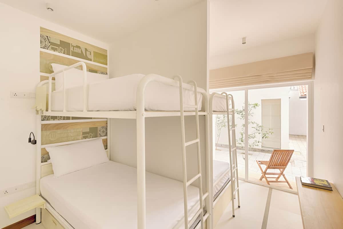 Habitación con literas, cabecera de madera, una mesita y una silla.
