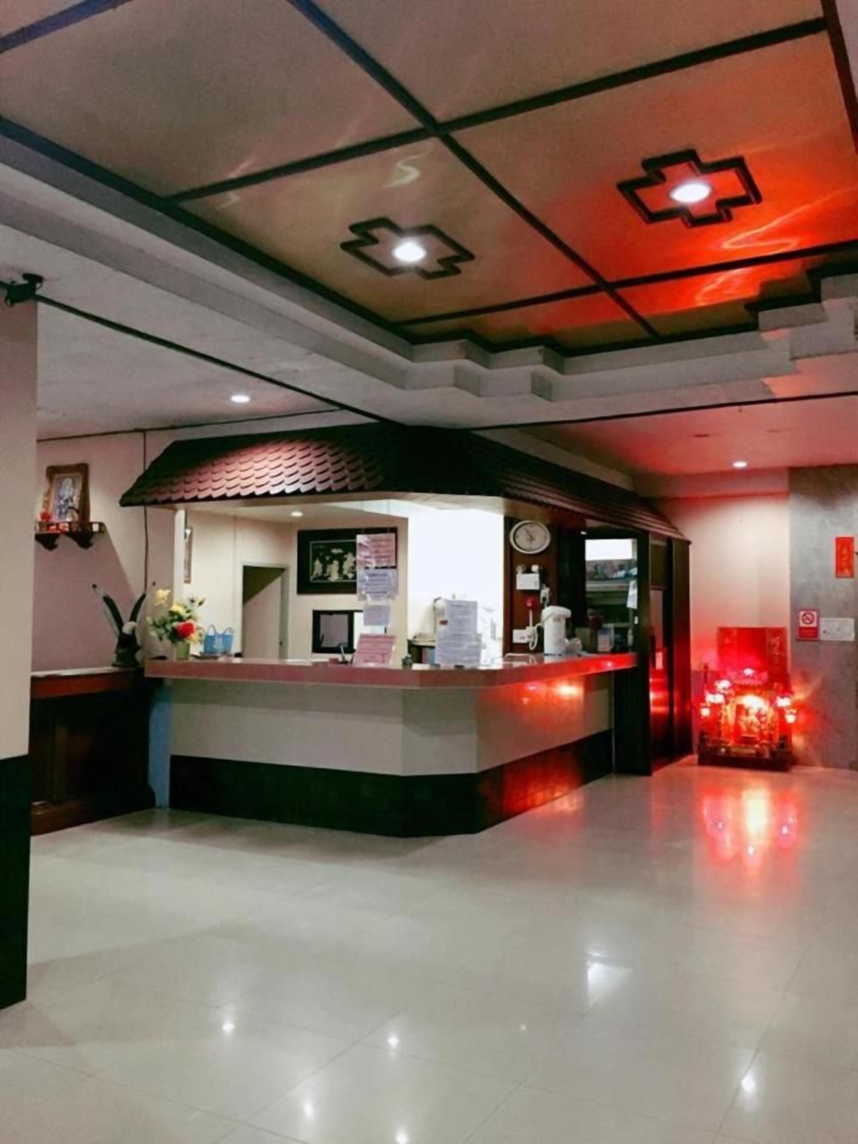 A hotel reception area with a counter, a clock, and a fire alarm.