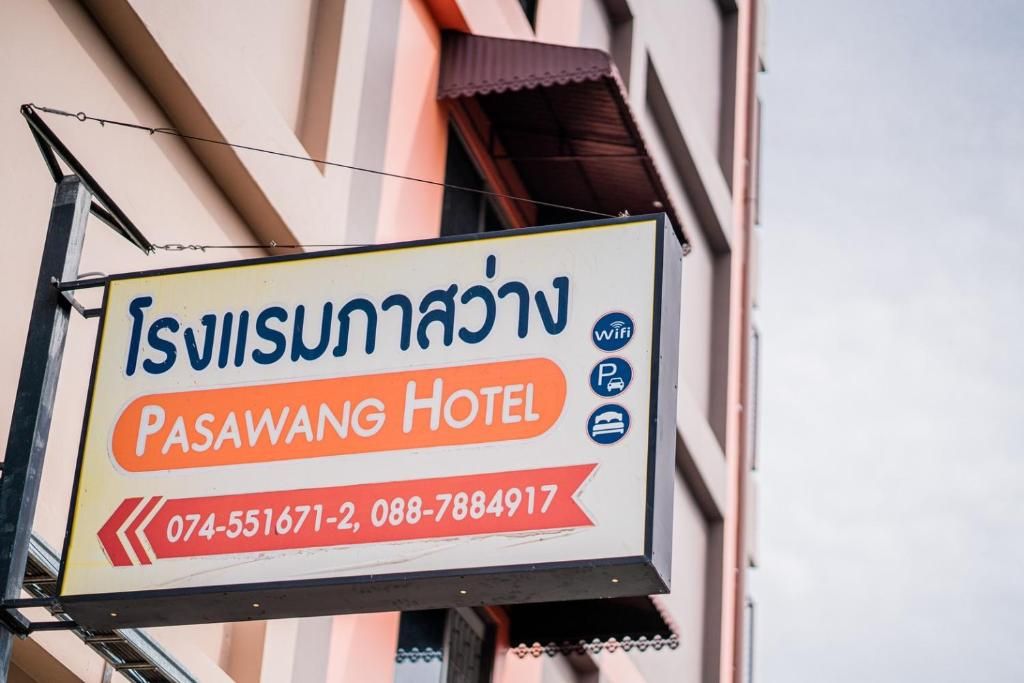 A hotel sign with Thai text and contact numbers.