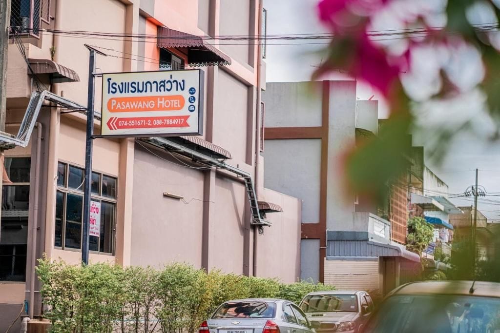 A building with a sign for Pasawang Hotel, including contact numbers.