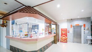 A reception area with a counter, a tiled floor, a ceiling with a decorative element, and a wall with a red decoration. - Pasawang hotel (Hat Yai)