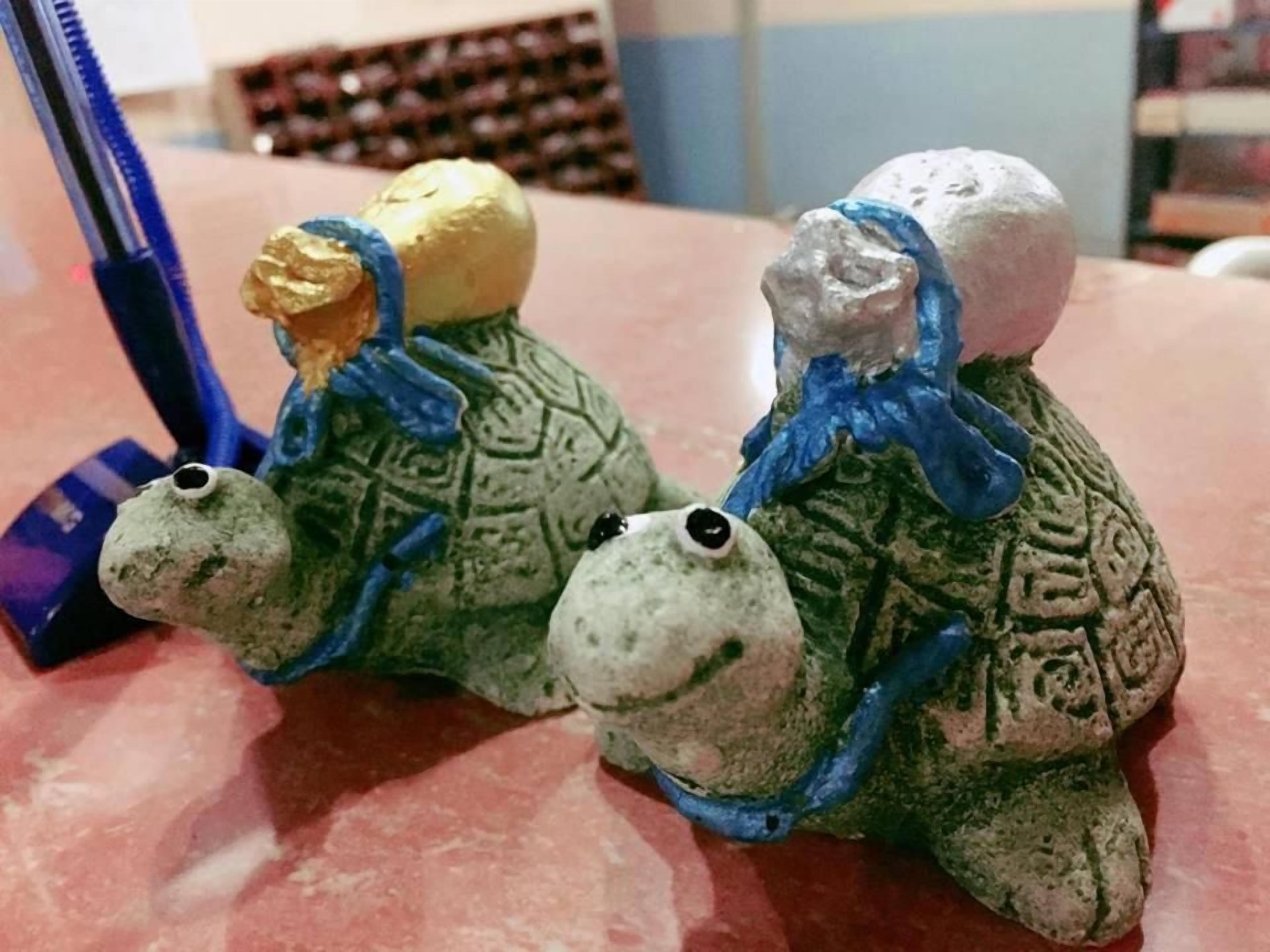 Dois sapos de cerâmica com fitas azuis sobre uma mesa.