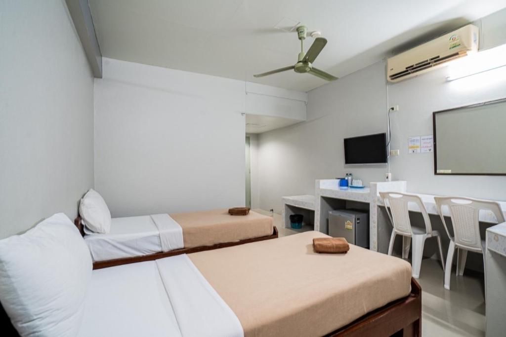Une chambre d’hôtel avec deux lits simples, un bureau avec une chaise, une télévision et un appareil de climatisation.