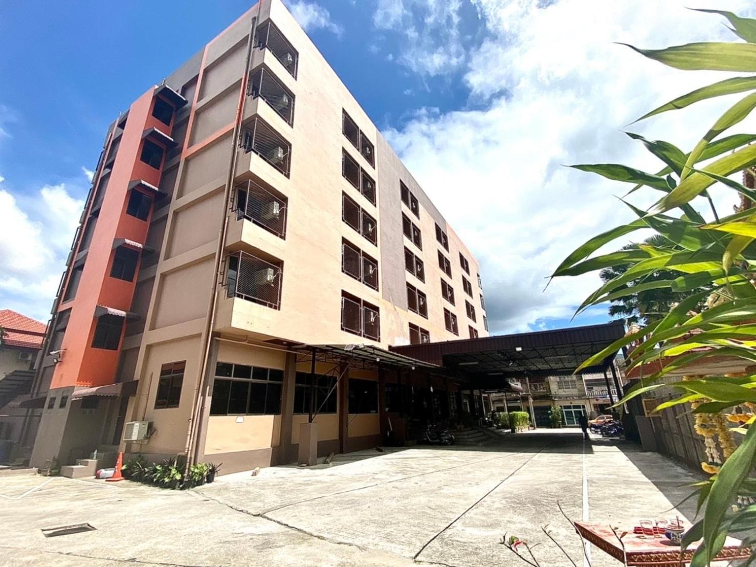Un edificio de varios pisos con un área de acceso techada y estacionamiento.