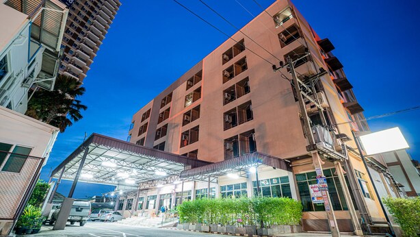 A multi-story hotel with a covered entrance, a parking area, and a view of the ocean. - Pasawang hotel (Hat Yai)