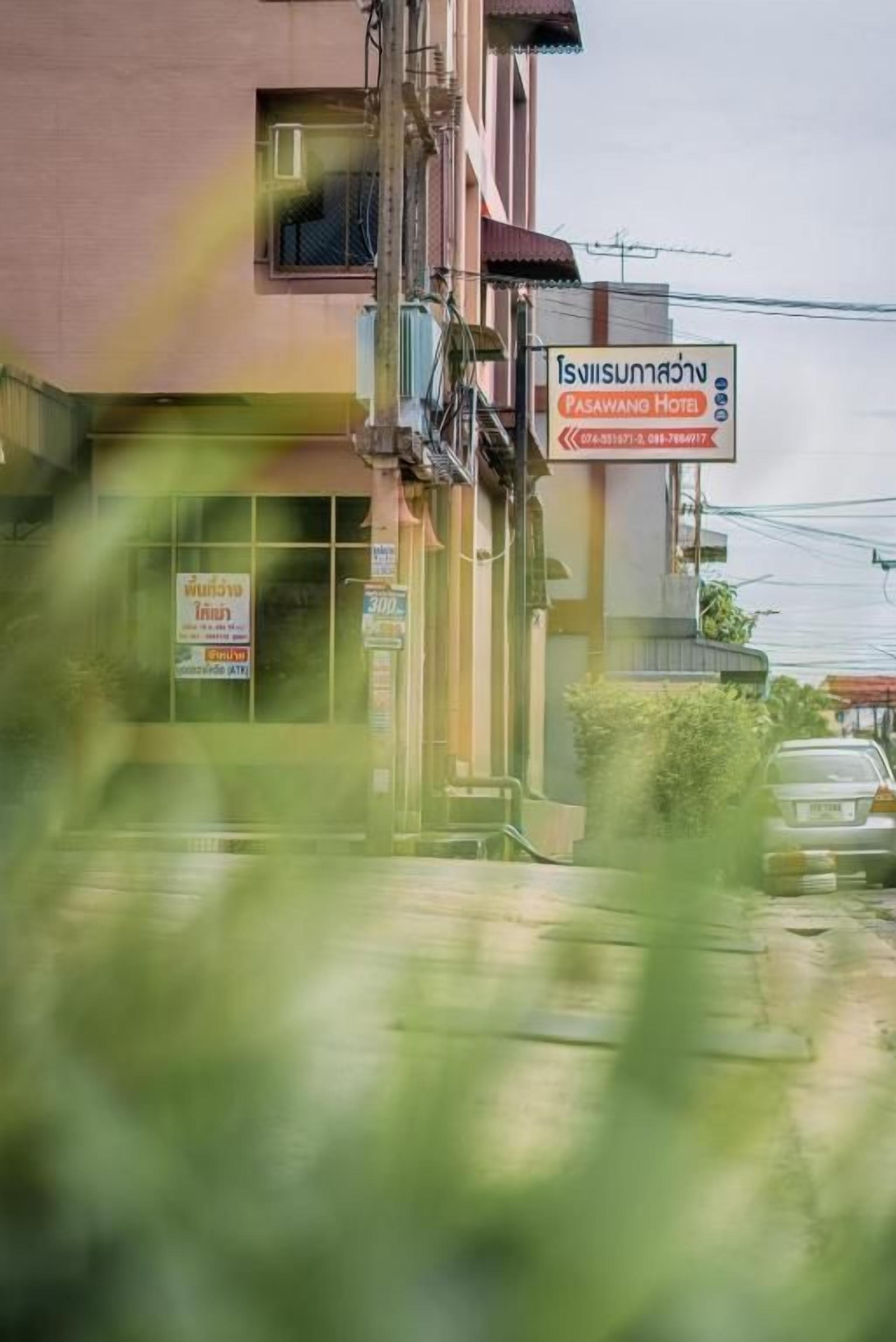 A building with a sign for Pasawang Hotel, including contact information and a website.