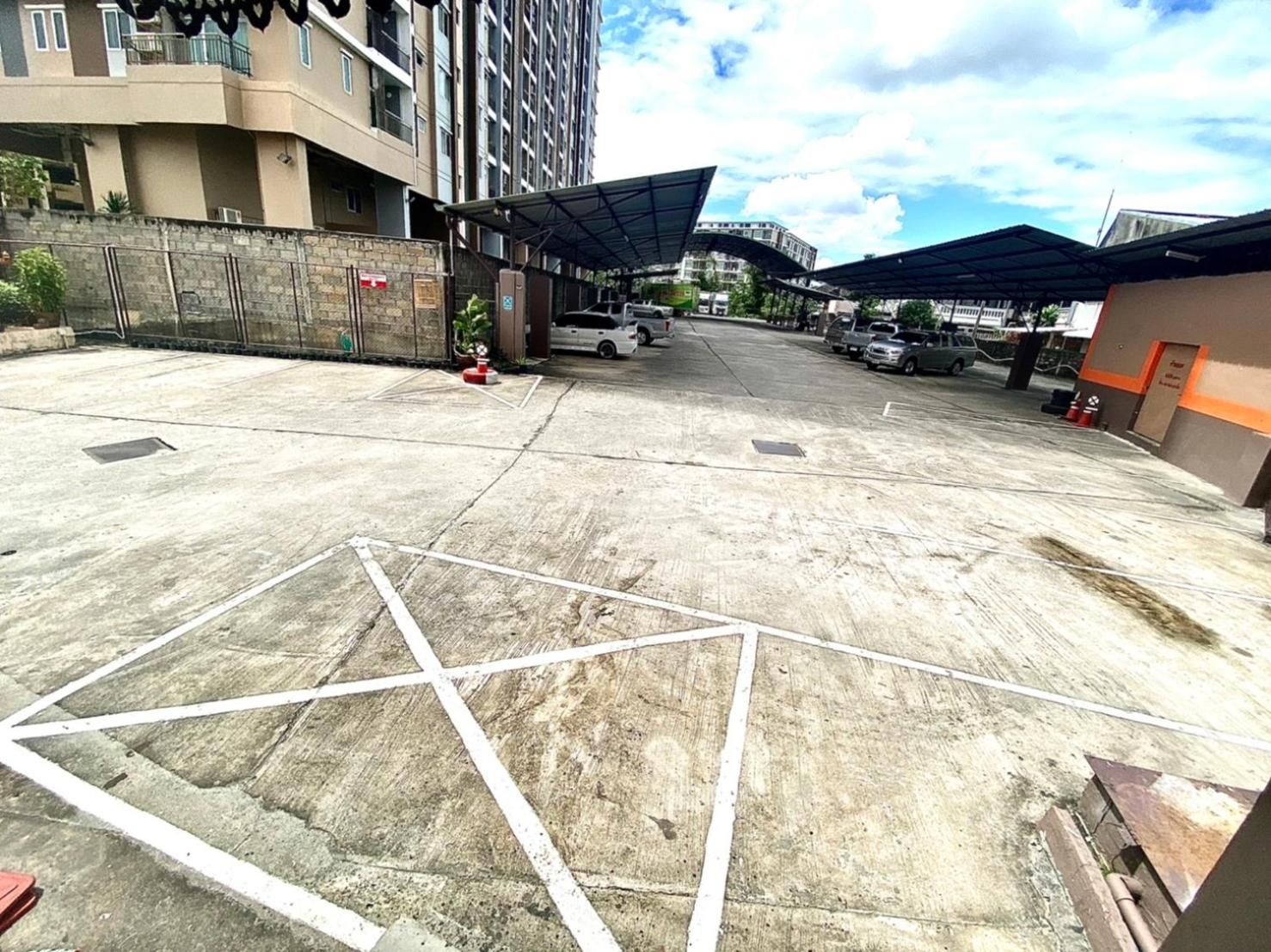A parking area with marked spaces, a covered entrance, and a building in the background.