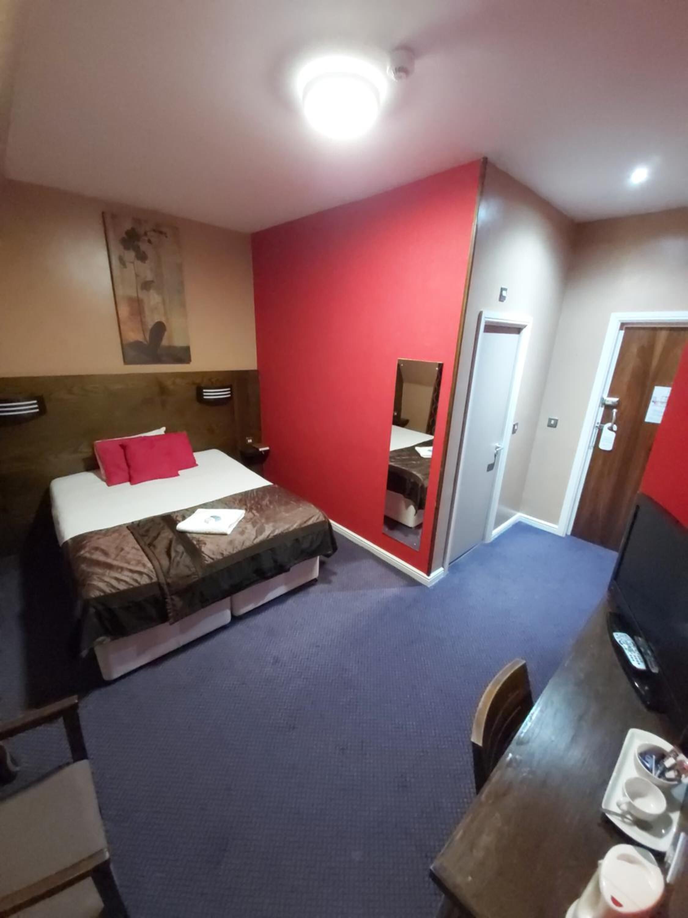 A hotel room with a bed, a desk, a chair, and a television.