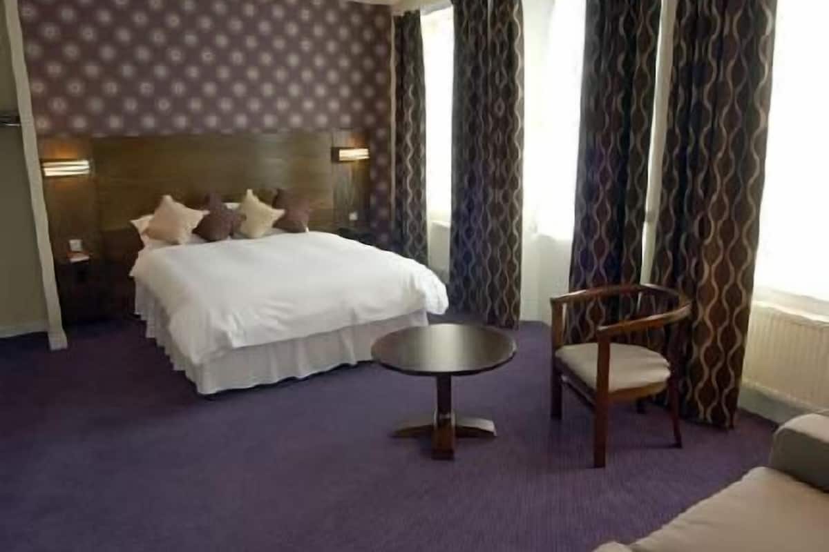 Una habitación de hotel con una cama, una mesa redonda y una silla.
