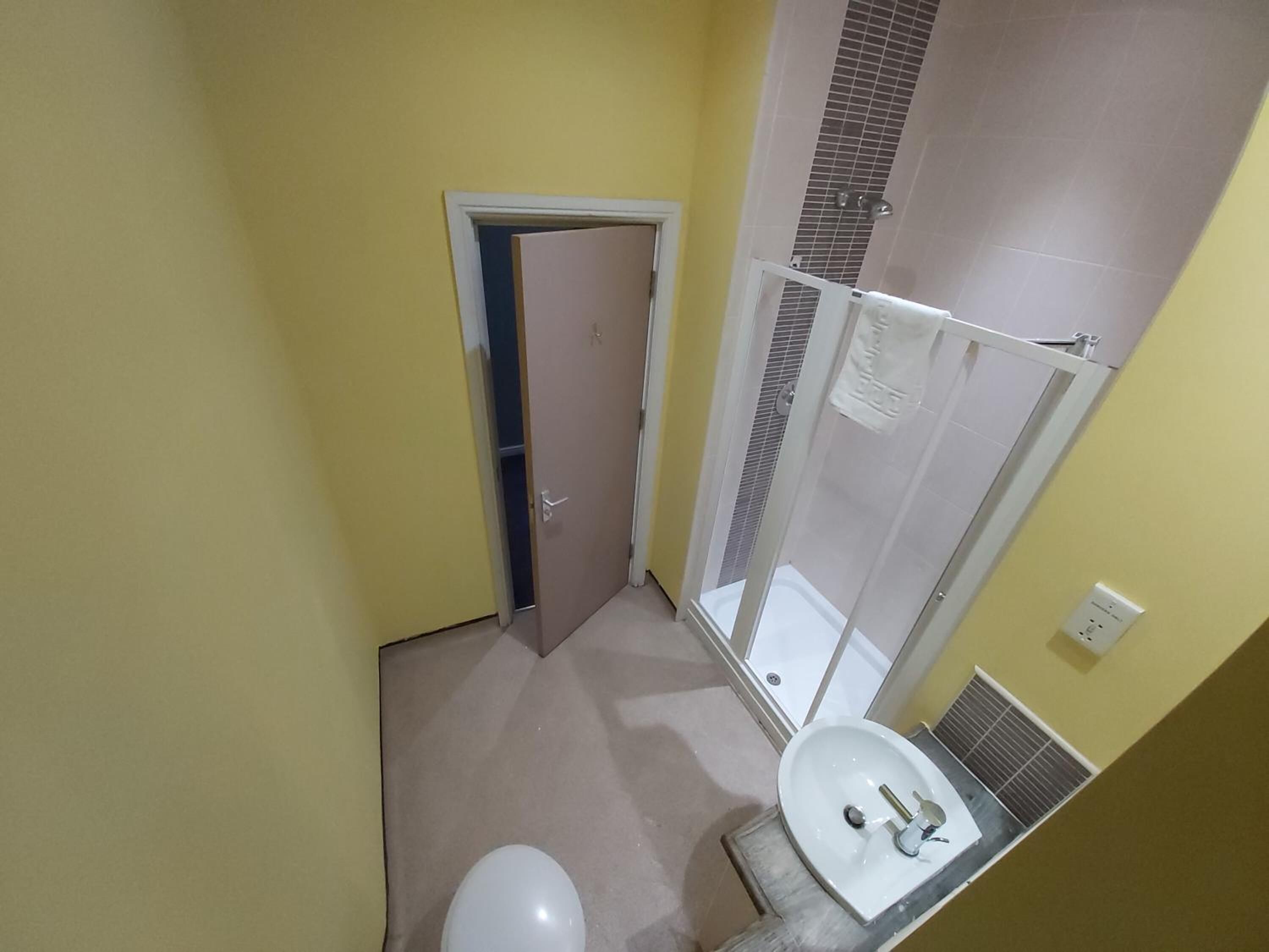 Et lille badeværelse med toilet, håndvask og bruser.