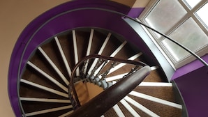 A spiral staircase with a purple and white color scheme, leading to a landing area with a window.