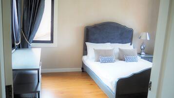 A neatly made bed with patterned pillows, a bedside lamp, and a window with curtains.