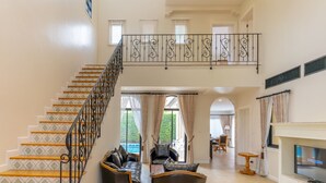 A spacious living area with a staircase, leather sofas, a TV, and a dining area. - Estella Pool Villas Pattaya (Sattahip)