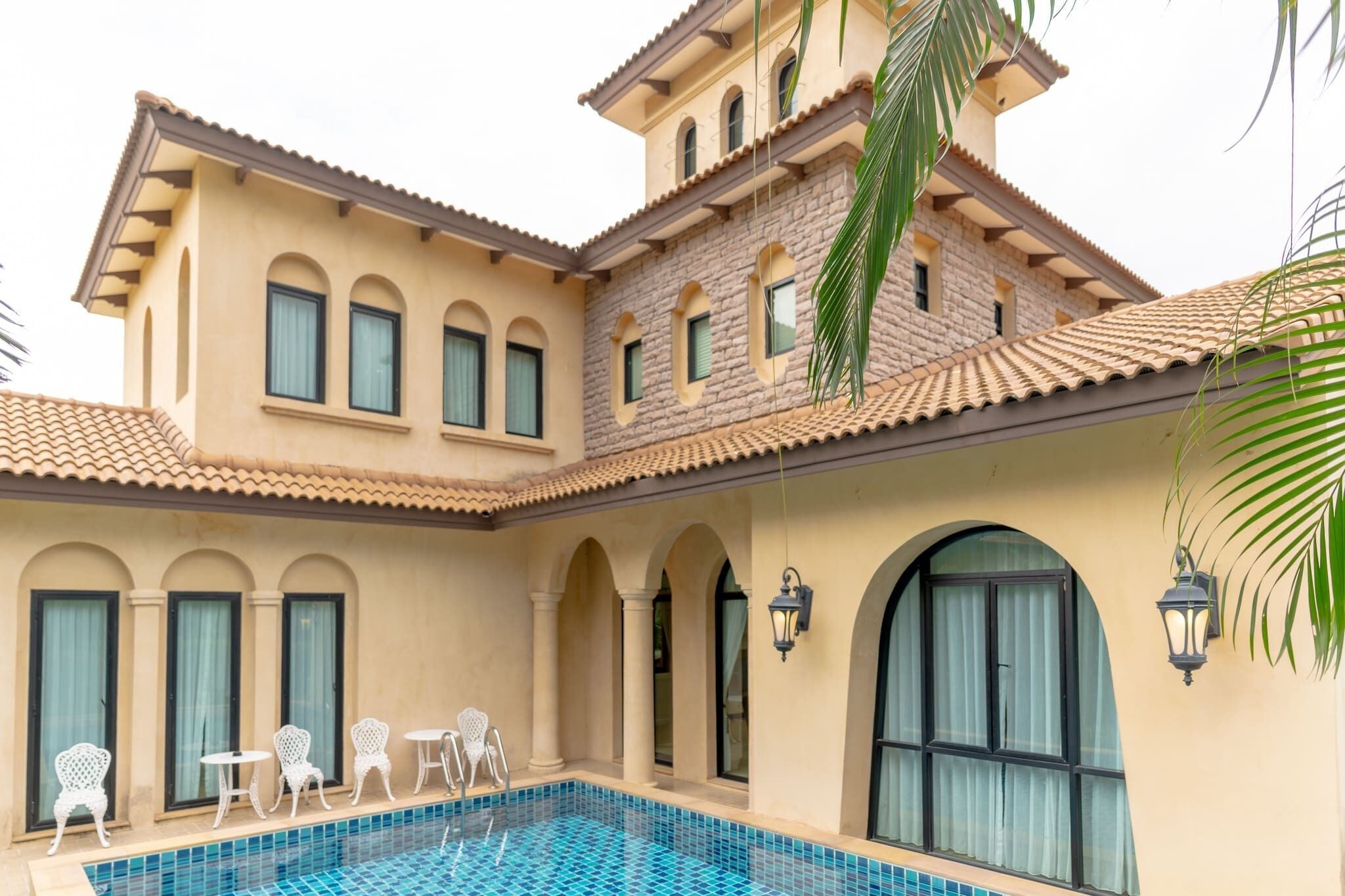 Un edificio de dos pisos con piscina, mobiliario exterior y fachada de piedra.