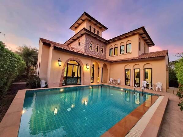 Una casa grande con piscina, varias puertas y ventanas de arco.