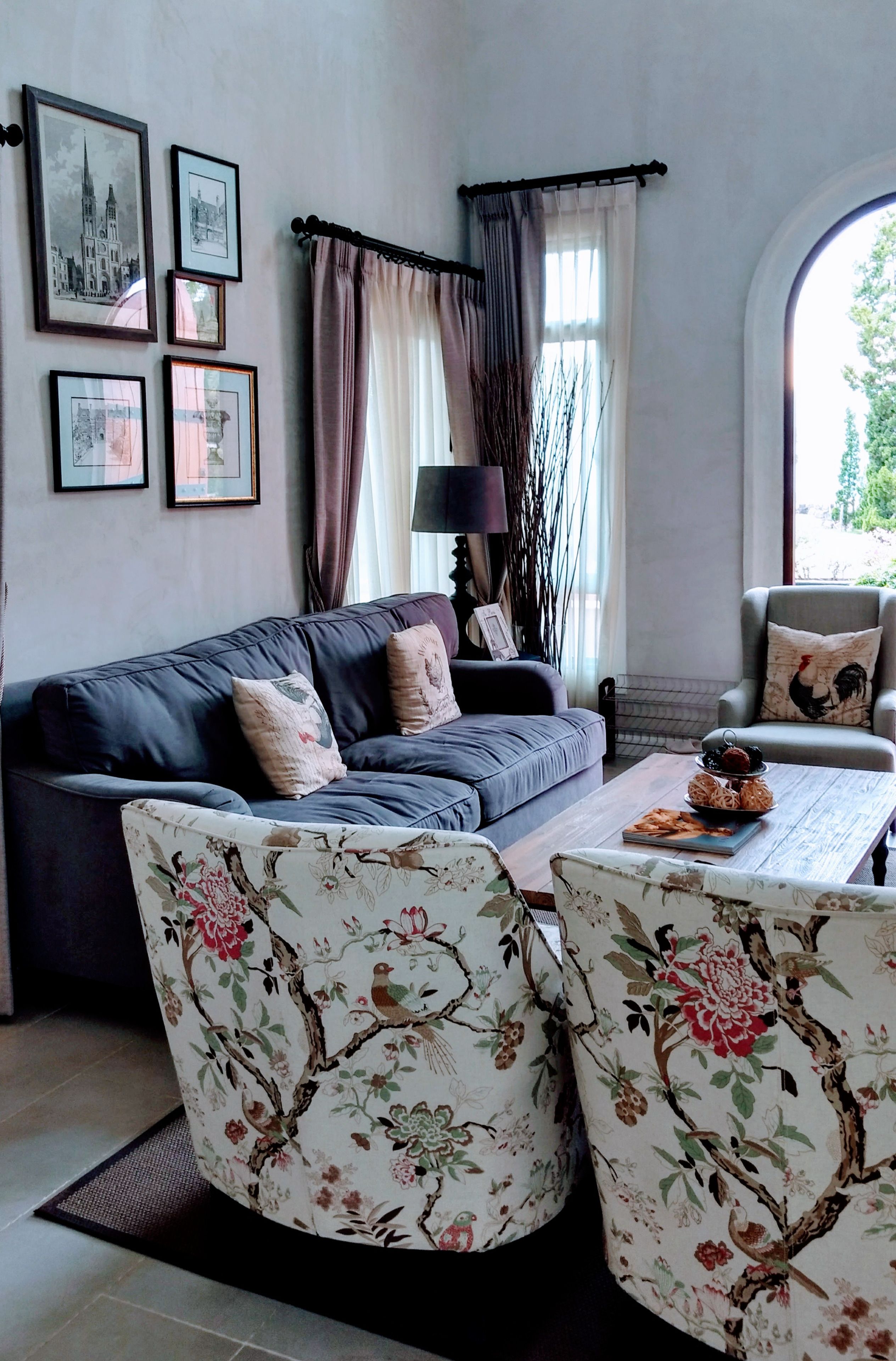 Una sala de estar con un sofá, dos sillones, una mesa de centro y una ventana con cortinas.