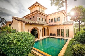 Una casa grande con piscina, arcos y una estructura tipo torre.