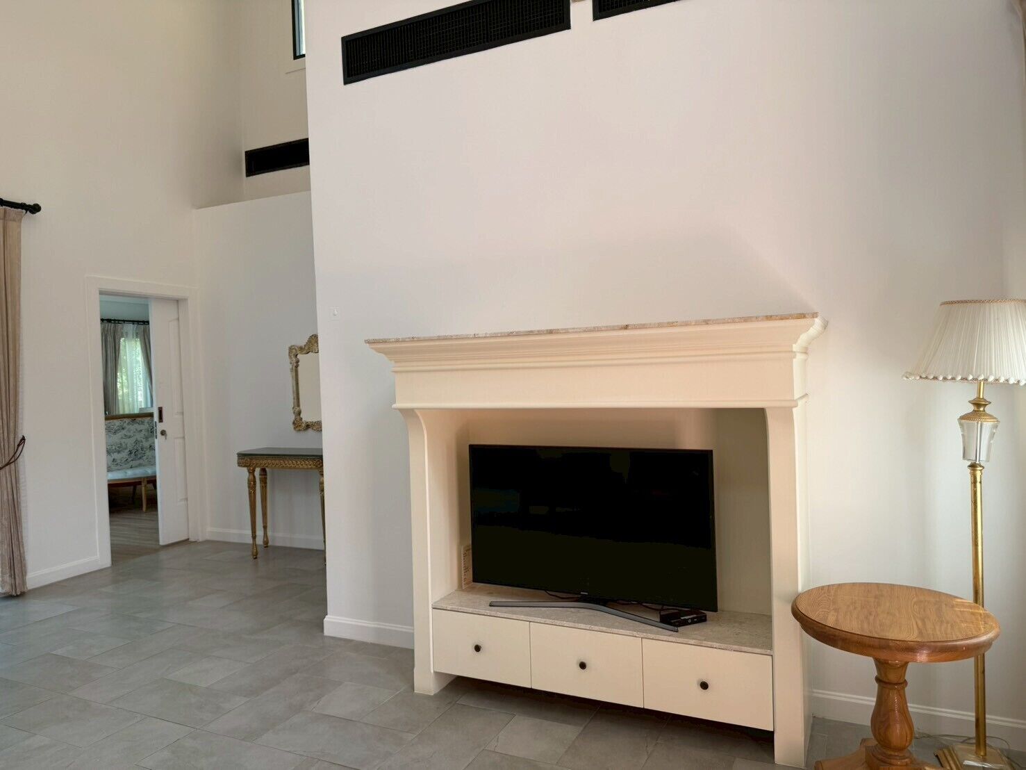 A room with a fireplace, a television, a small table, and a lamp.