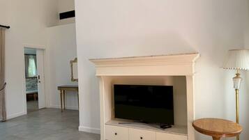 A room with a fireplace, a television, a small table, and a lamp.
