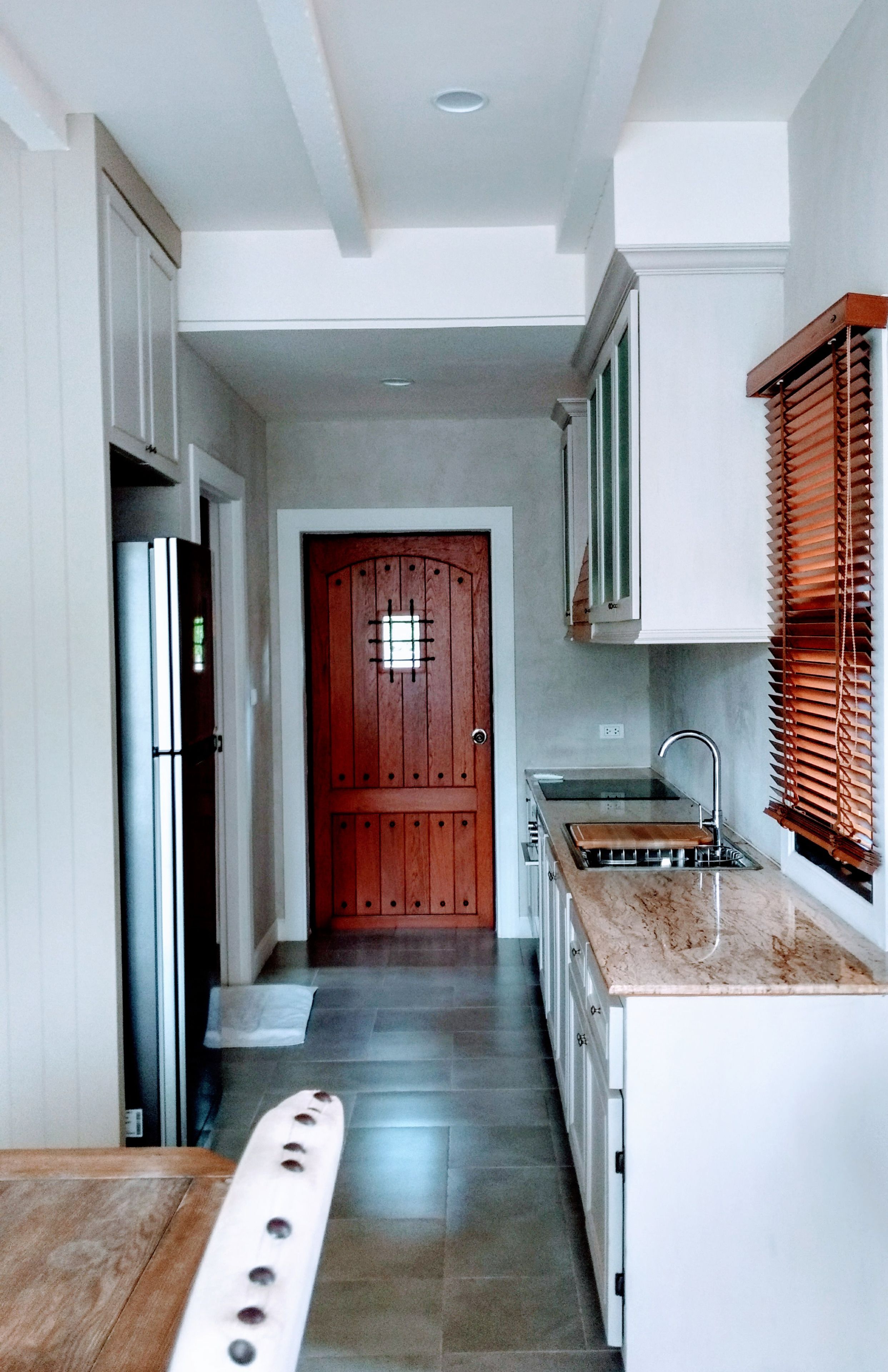 A narrow kitchen with a wooden door, a built-in sink, and a countertop.