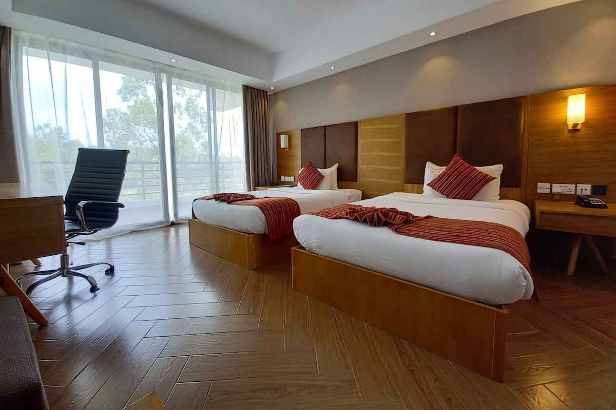 Une chambre d’hôtel avec deux lits, un bureau et une chaise.