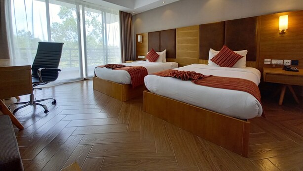 A hotel room with two beds, a desk, and a chair.