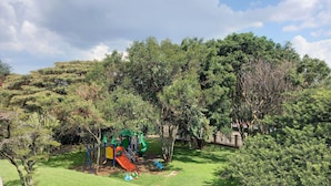 A grassy area with a playground, a table with chairs, and a fence.