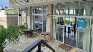 A hotel exterior with a stone facade, large glass doors, outdoor seating, and a view of the surrounding area.