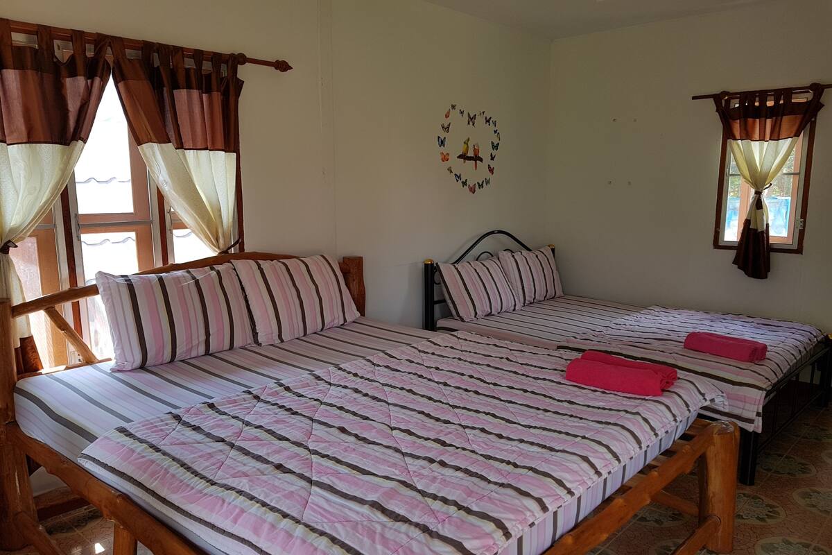 Un dormitorio con dos camas, cabeceros de madera, ropa de cama a rayas y cortinas.