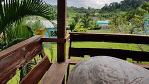 A wooden bench overlooking a lush green landscape with a view of a house and trees. - Baan Phanawan Resort (Khao Kho)