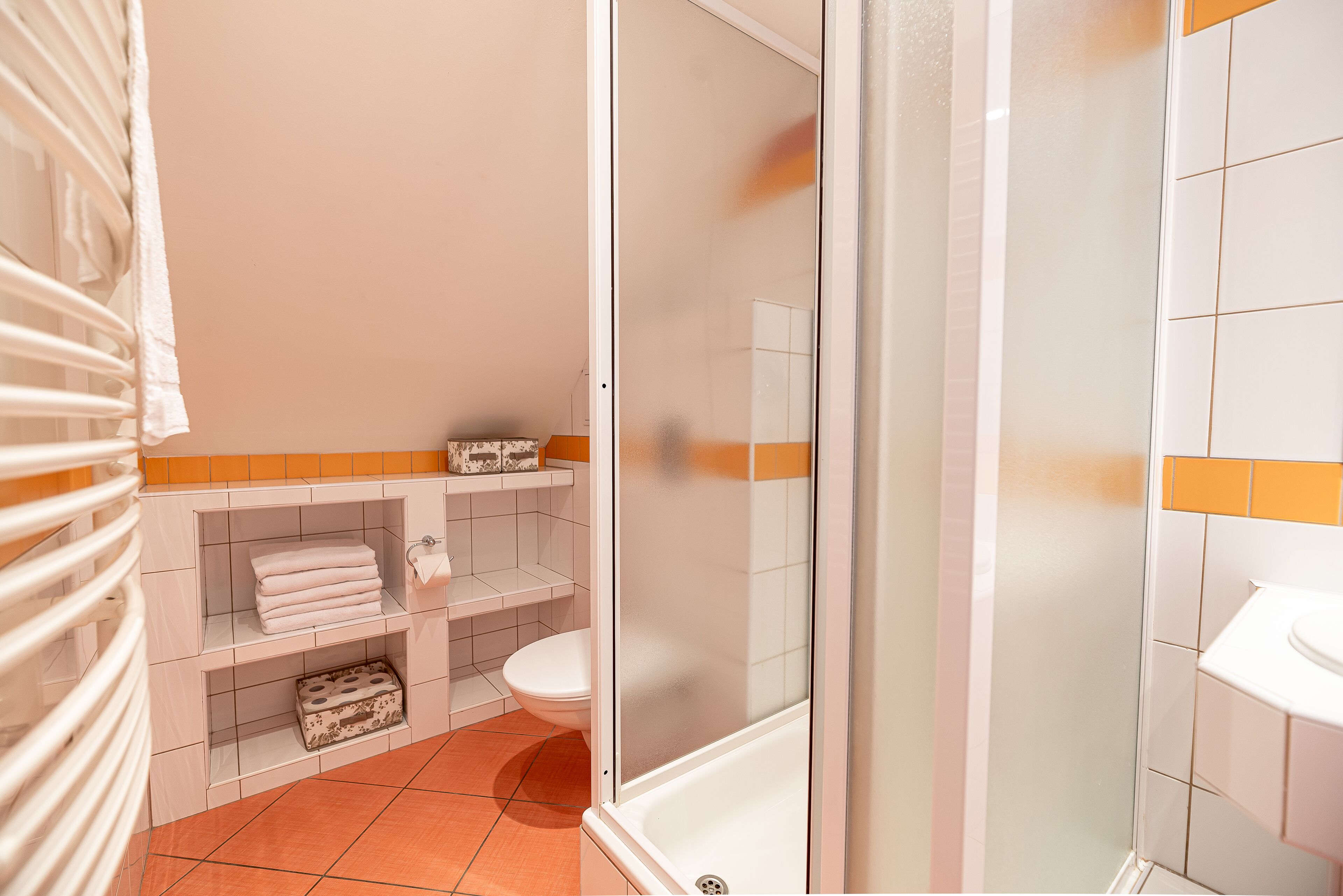 A bathroom with a toilet, a sink, a shower enclosure, and a towel rack.