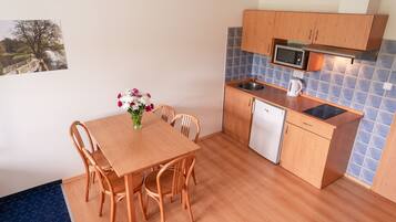 A compact kitchen with wooden cabinets, a microwave, a sink, and a dishwasher.