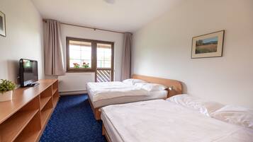 A hotel room with two beds, a desk with a computer, a window with curtains, and a framed picture on the wall.