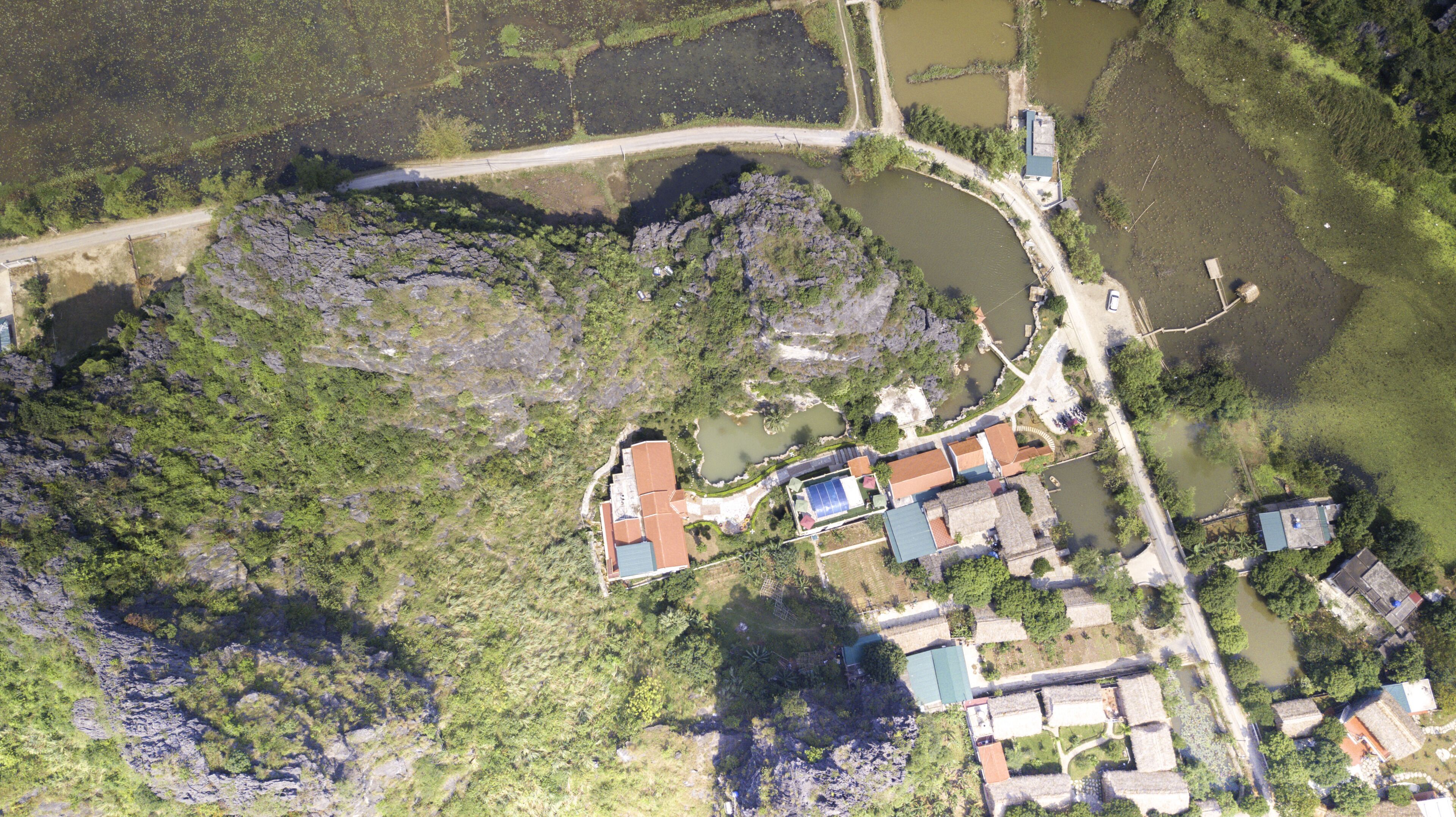 An aerial view of a small settlement with a mix of residential and commercial buildings, surrounded by natural landscapes and water bodies.