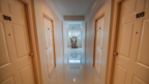 Un couloir d’hôtel avec des portes numérotées 106 et 105, qui donnent sur une chambre dotée d’une grande fenêtre et ornée d’un élément décoratif sur le mur.