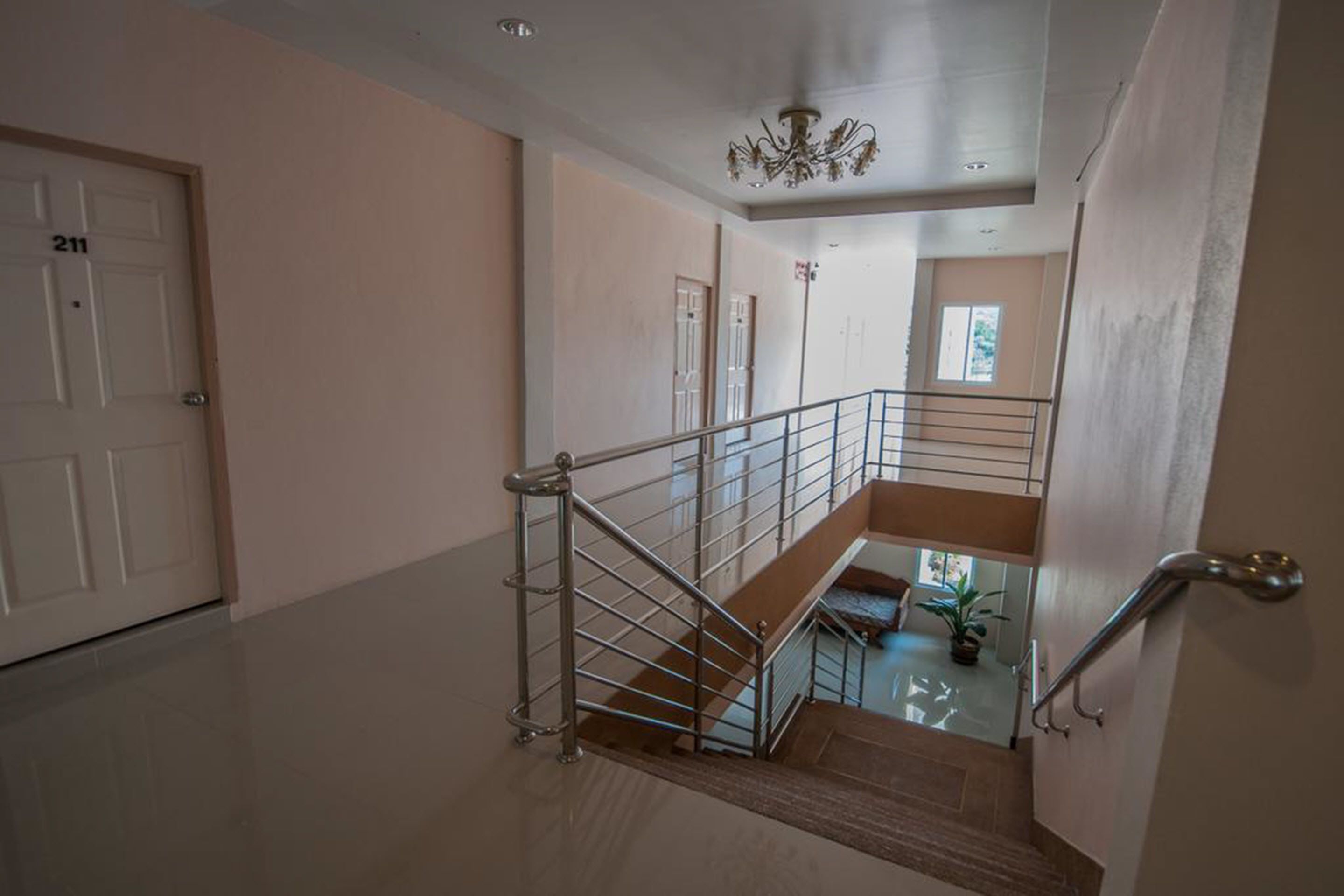 A multi-level interior with a staircase, a chandelier, and a door marked with the number 211.